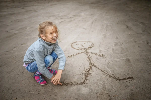 Pequena areia menina desenha homem engraçado — Fotografia de Stock