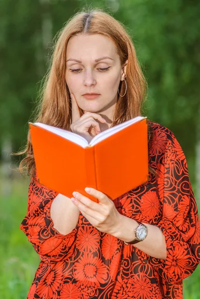 Kvinna i röd klänning läsa bok — Stockfoto