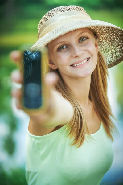 Porträtt av ung kvinna som bär stråhatt hålla telefon — Stockfoto