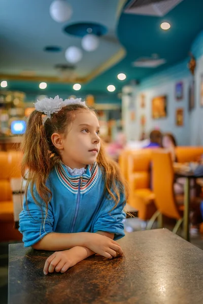 Little girl sitting at a table — Stock Photo, Image