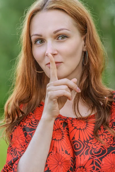 Mujer en vestido rojo poner dedo a los labios —  Fotos de Stock