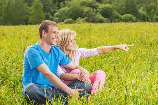 Jeune couple assis sur l'herbe — Photo