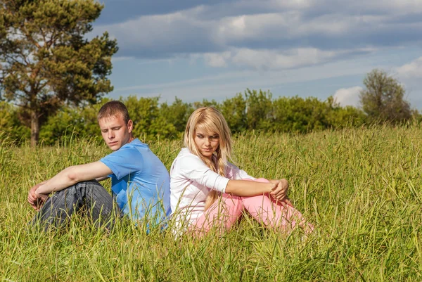 Jovem casal senta-se na grama — Fotografia de Stock