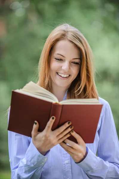 Sorridente giovane donna che legge libro — Foto Stock