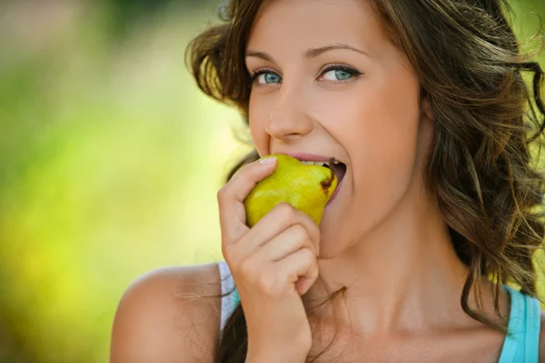 Woman close-up in blue shirt pear bites — Stock Photo, Image