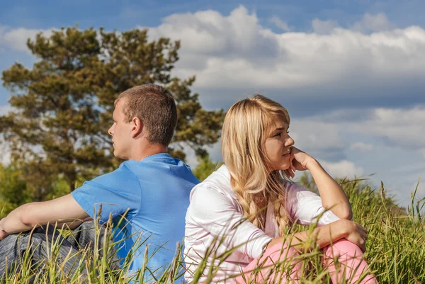 Young couple sits on grass — Stock Photo, Image