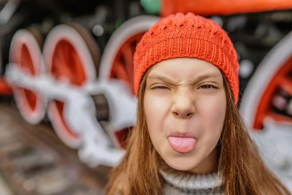 빨간 모자에서 소녀 혀를 보여줍니다. — 스톡 사진
