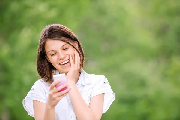 携帯電話で笑顔の若い女性 — ストック写真