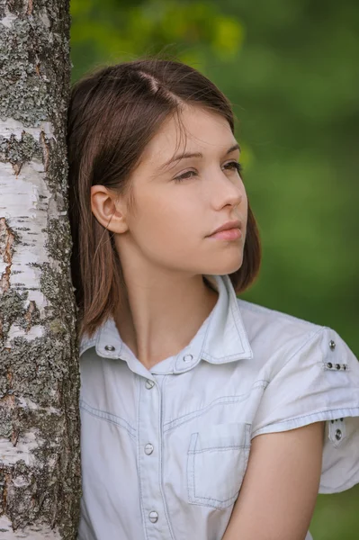 Huş ağacı kucaklayan genç esmer kadın portresi — Stok fotoğraf