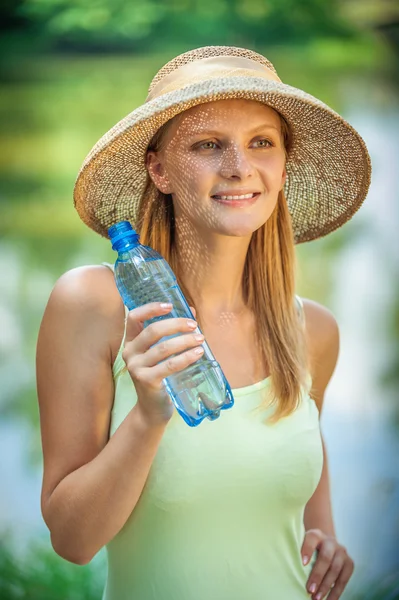 Chica en sombrero de paja bebe agua —  Fotos de Stock