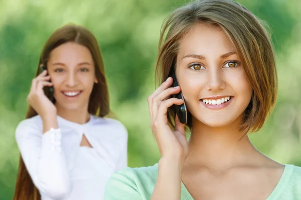 Smiling teenage girls talking on mobile phone — Stock Photo, Image