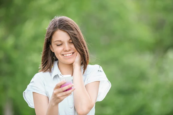 Unga leende kvinna med mobiltelefon — Stockfoto