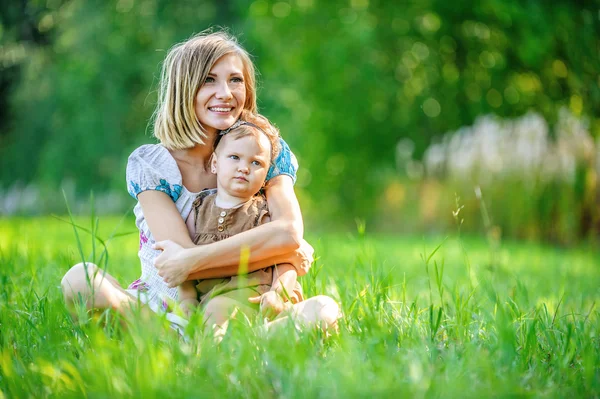 Vacker ung mamma dotter avkopplande sittande gräs — Stockfoto