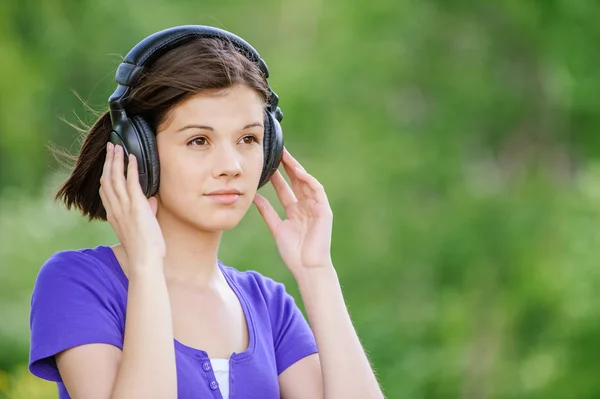 Närbild porträtt av ung kvinna som bär hörlurar — Stockfoto