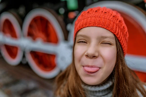 Lilla flickan i röd hatt visar tungan — Stockfoto