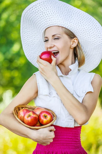 Женщина с плетеной корзиной держит красные яблоки — стоковое фото