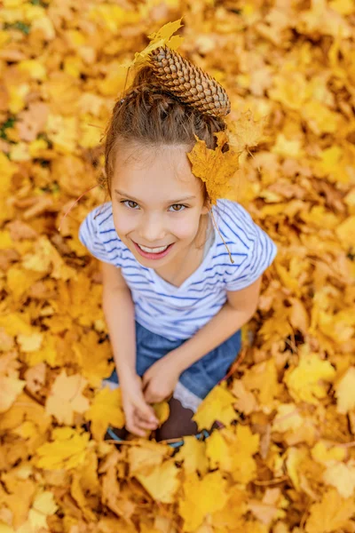 Meisje begraven in het najaar van bladeren gele — Stockfoto