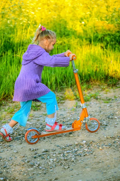 Petite fille est en scooter — Photo