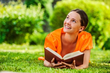 genç kadın kitap ile çim üzerinde yalan