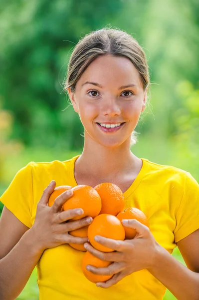 Молодая женщина в желтой блузке с апельсинами — стоковое фото