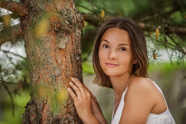 Mladá žena poblíž kmen stromu — Stock fotografie