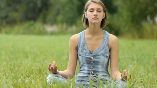 Mujer meditando sentada en la hierba — Vídeos de Stock