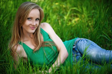 Yeşil çimenlerin üzerinde oturan güzel kadın