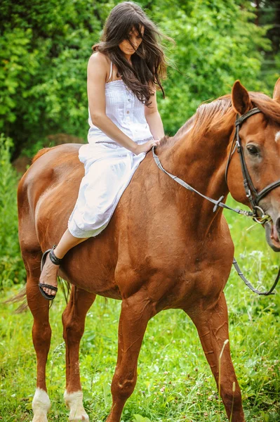 Jonge brunette vrouw rijdt een paard — Stockfoto