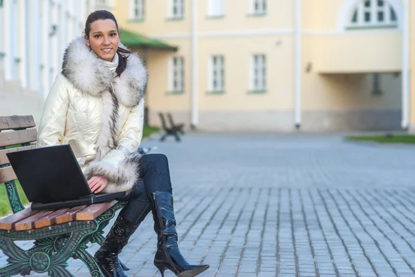 Woman in white coat sitting on bench — Stock Photo, Image