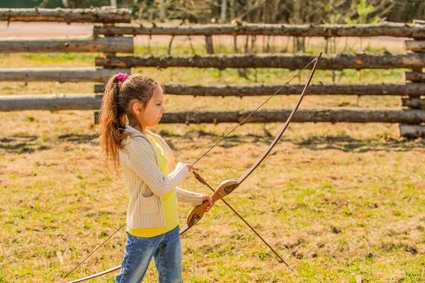 Маленькая девочка стреляет в лук — стоковое фото