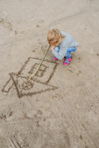 Little girl draws in the sand — Stock Photo, Image