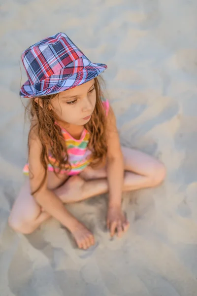 Маленькая девочка сидит на песке — стоковое фото