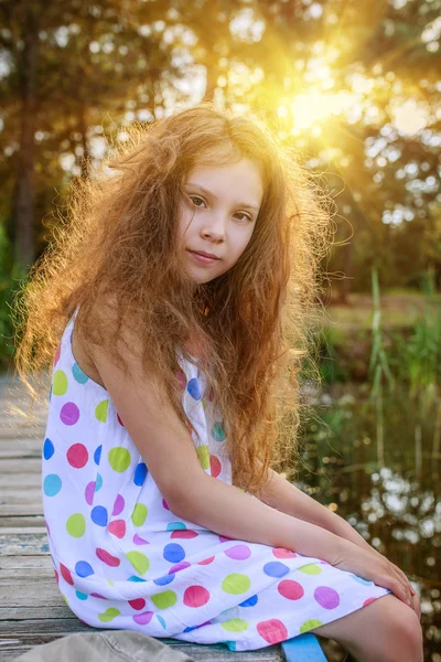 Little beautiful girl sitting on bridge — Stock Photo, Image