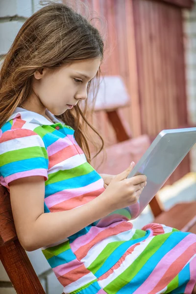 Маленькая спокойная девочка играет на планшетном ПК — стоковое фото