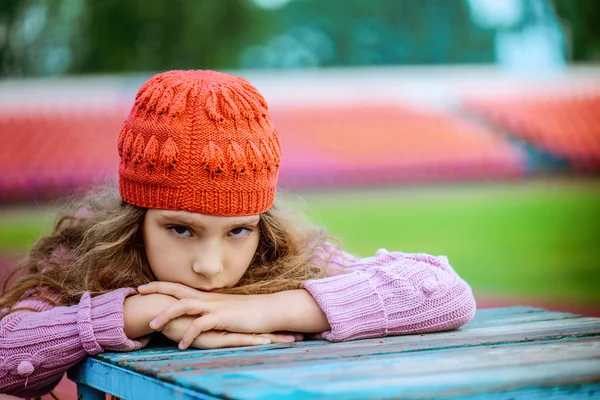 Pequena menina bonita em um boné vermelho no estádio — Fotografia de Stock