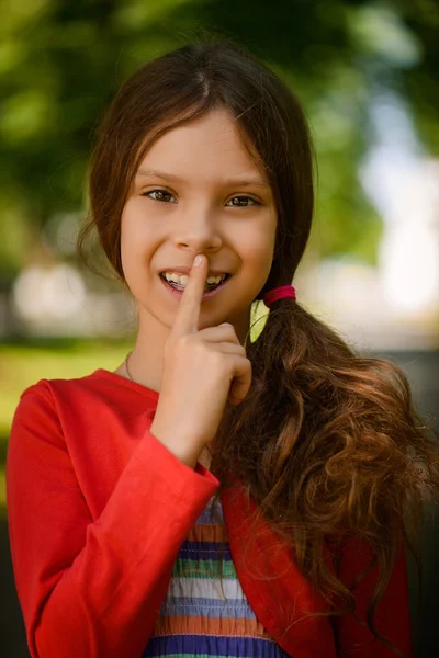 Pequena menina sorrindo coloca o dedo em sua boca — Fotografia de Stock