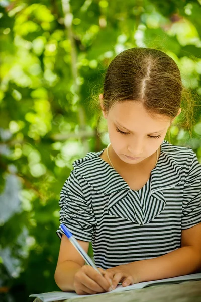 Маленькая девочка пишет ручку в блокноте — стоковое фото