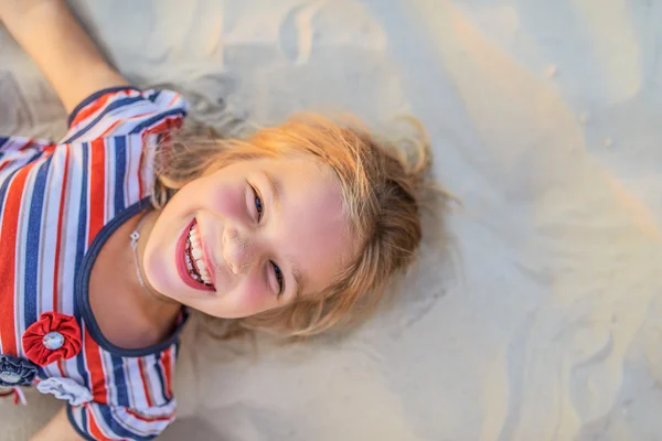 Smiling little girl lies on beach sand — Φωτογραφία Αρχείου