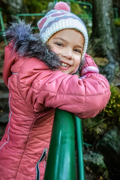 Усміхнена маленька дівчинка в червоній зимовій куртці — стокове фото