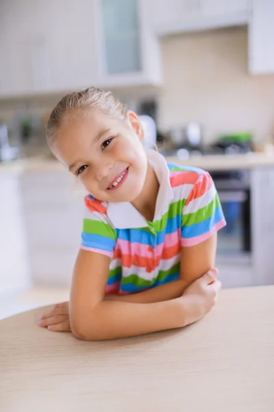 小さな女の子のテーブルに座って、笑顔 — ストック写真