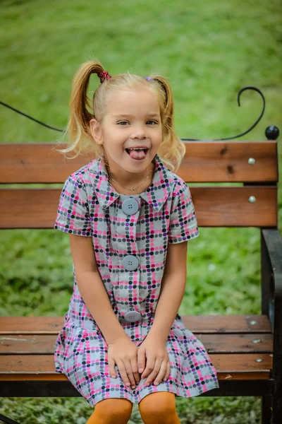 Маленькая девочка сидит на скамейке — стоковое фото