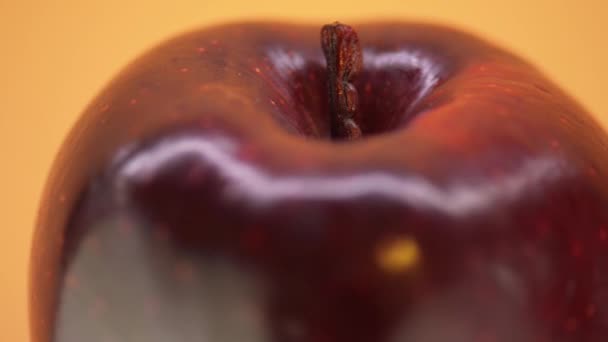 Kreisförmige Bewegung: großer roter Apfel auf orangefarbenem Hintergrund. — Stockvideo