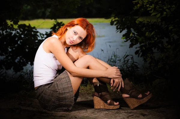 Mooie vrouw zittend op de oever van lake — Stockfoto