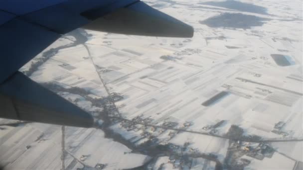 Avión vuela sobre campos cubiertos de nieve — Vídeos de Stock