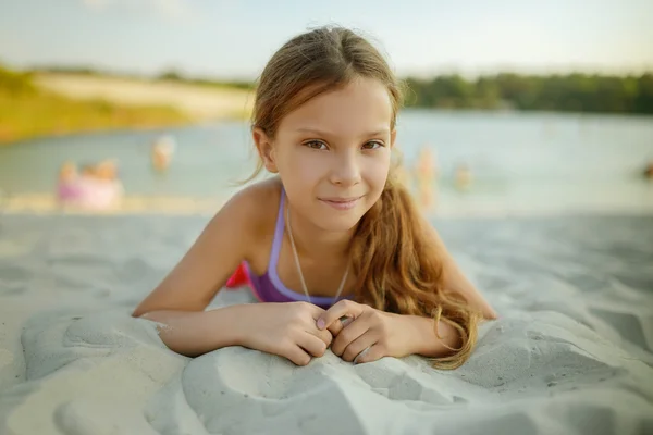 Küçük güzel gülümseyen kız sıcak kum üzerinde yalan — Stok fotoğraf