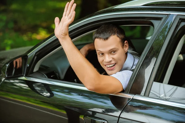 Porträtt av ung man kör bil och hälsning någon med han — Stockfoto