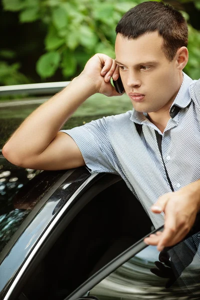 Ung man talar på telefon om bilen — Stockfoto