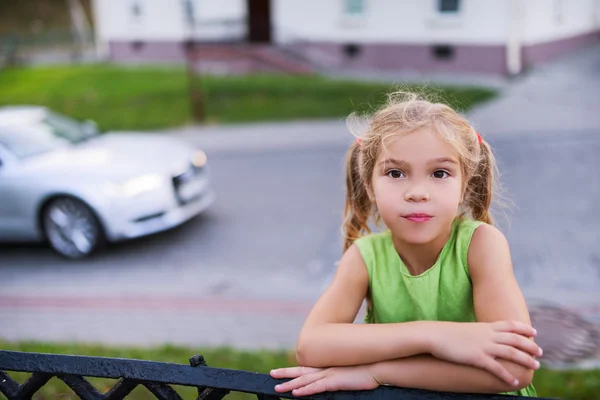 Kleines nachdenkliches Mädchen vor vorbeifahrendem Auto — Stockfoto