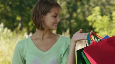 birçok çanta tutan genç gülümseyen kadın portresi