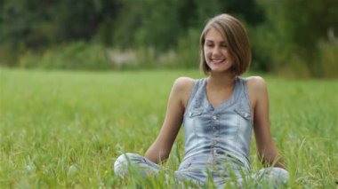 çimlerde oturan genç kadın gülüyor